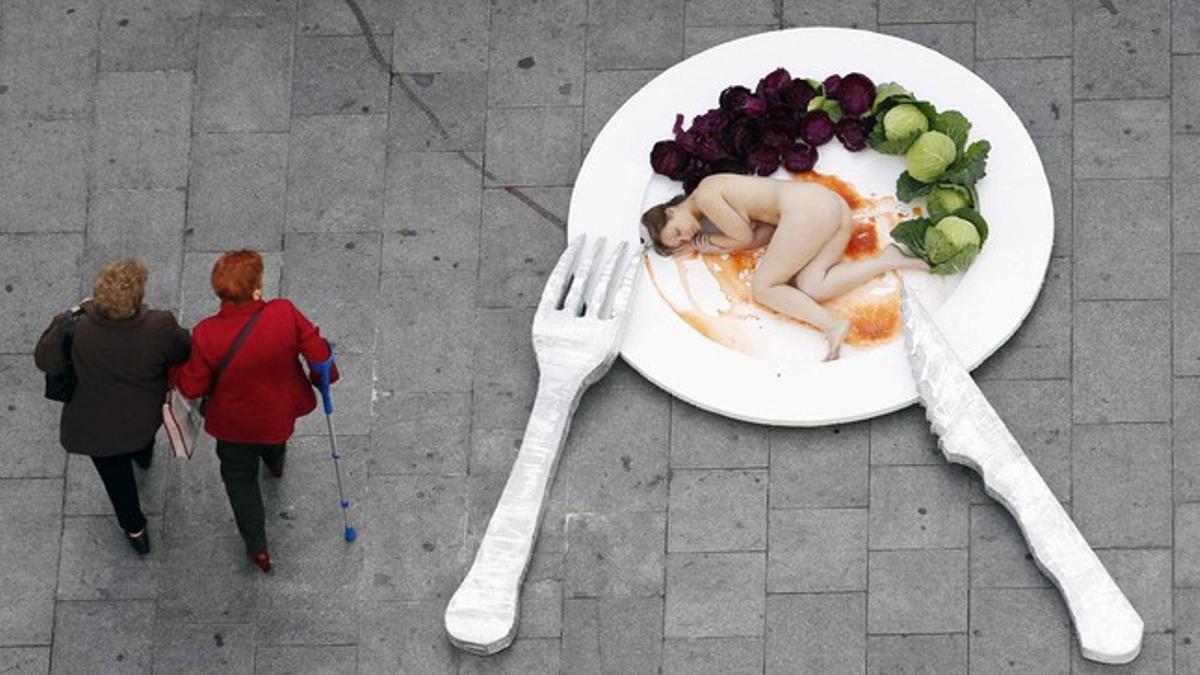 Dos personas pasan junto a la 'performance' realizada en el centro de Barcelona.