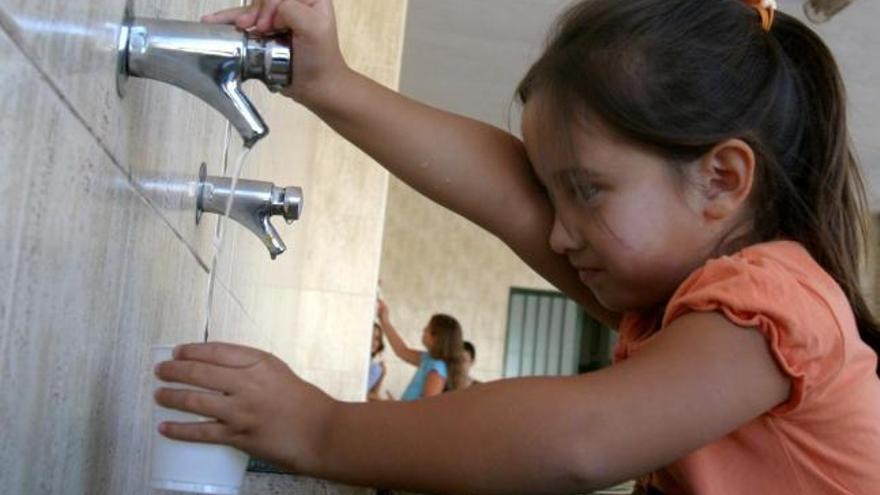 Una niña bebe agua del grifo.