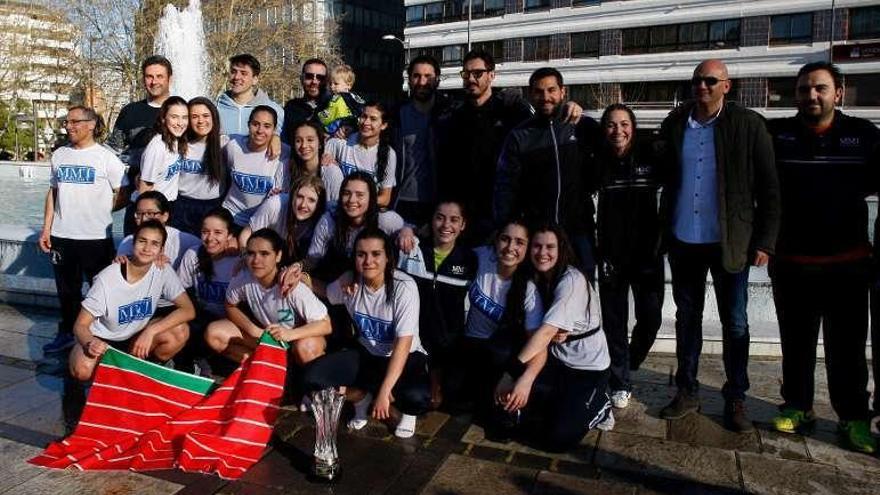 El equipo posa con el trofeo acompañado por miembros del club.