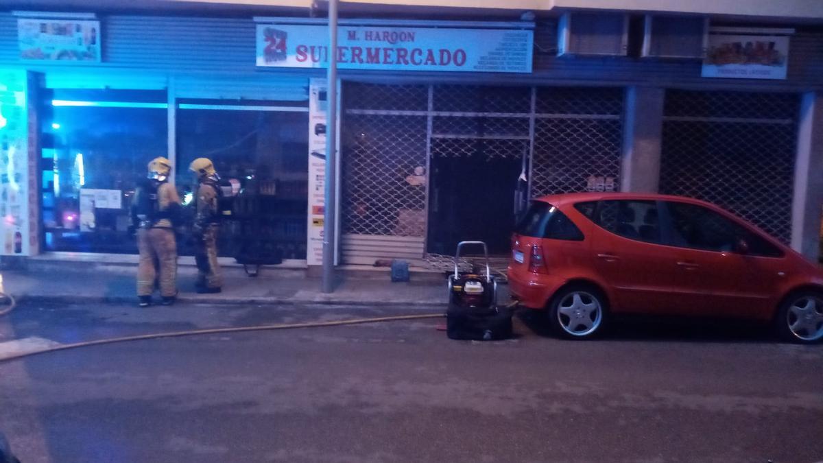 Los bomberos, frente al supermercado incendiado.