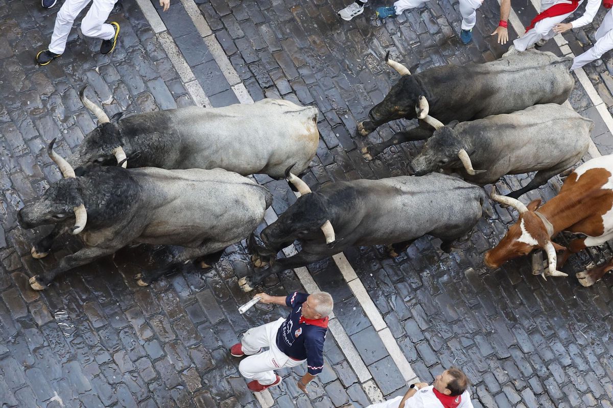 PAMPLONA, 12/07/2025.- Mozos perseguidos por los toros de la ganadería de José Escolar en el sexto encierro de los Sanfermines, este sábado en Pamplona. EFE/ Villar López