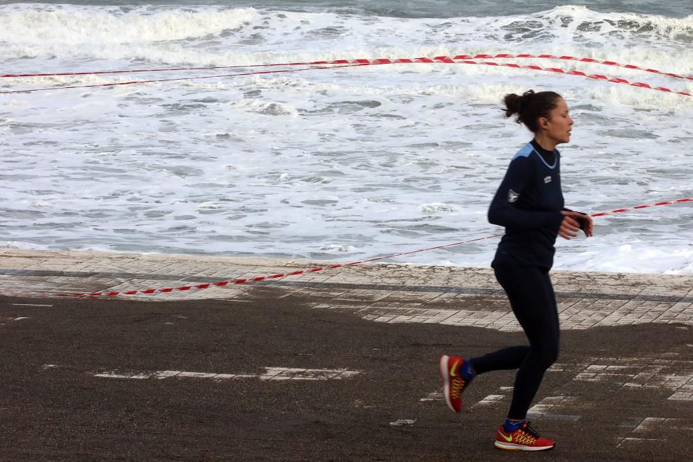 El fuerte oleaje lleva el agua hasta el paseo marítimo y atrae a numerosos curiosos a inmortalizar la estampa