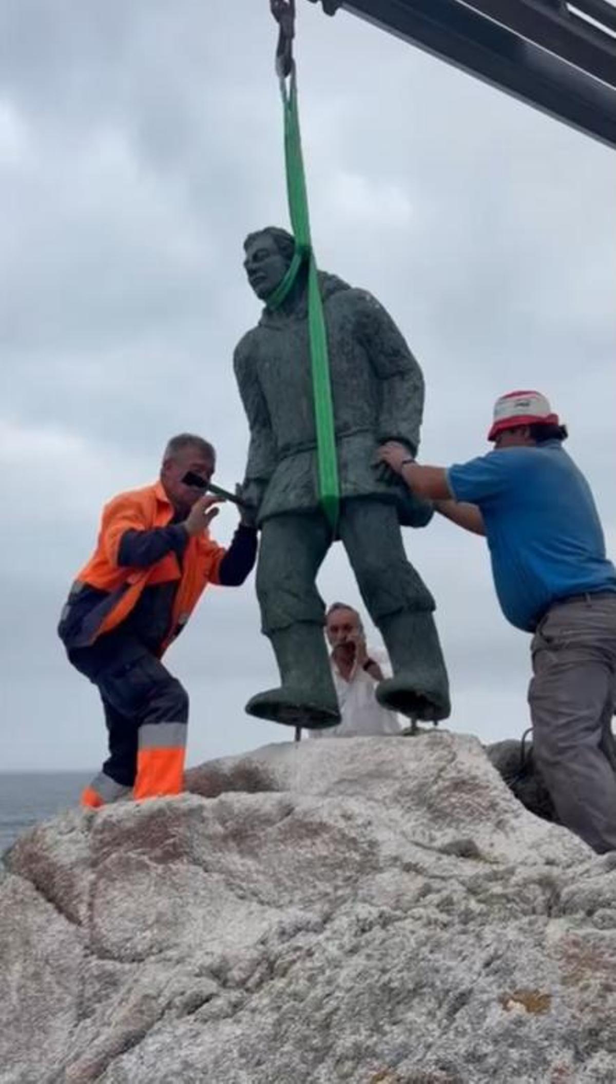 Operarios instalando a escultura do percebeiro sobre as rochas.