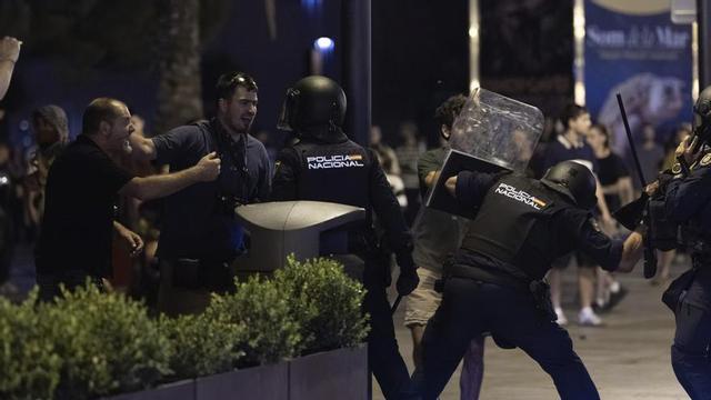 A la derecha, un agente de la Policía Nacional a punto de impactar con la porra contra un manifestante.  | TOMÀS MOYÀ / EUROPA PRESS