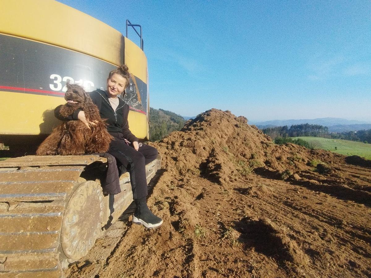 Alexandra Beliba junto a su perro, XXXXXXX, sentada en la excavadora que ha comenzado el movimiento de tierras en su finca de Villamuñín.