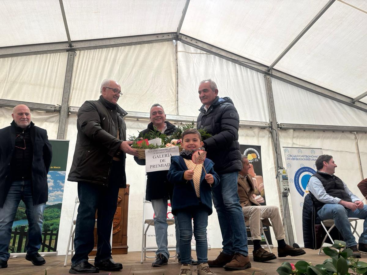 Emilio Rubio, con su nieto Marco, reciben de manos de Pepe Sariago (izquierda) y Fernando Delgado la cesta de quesos subastados.