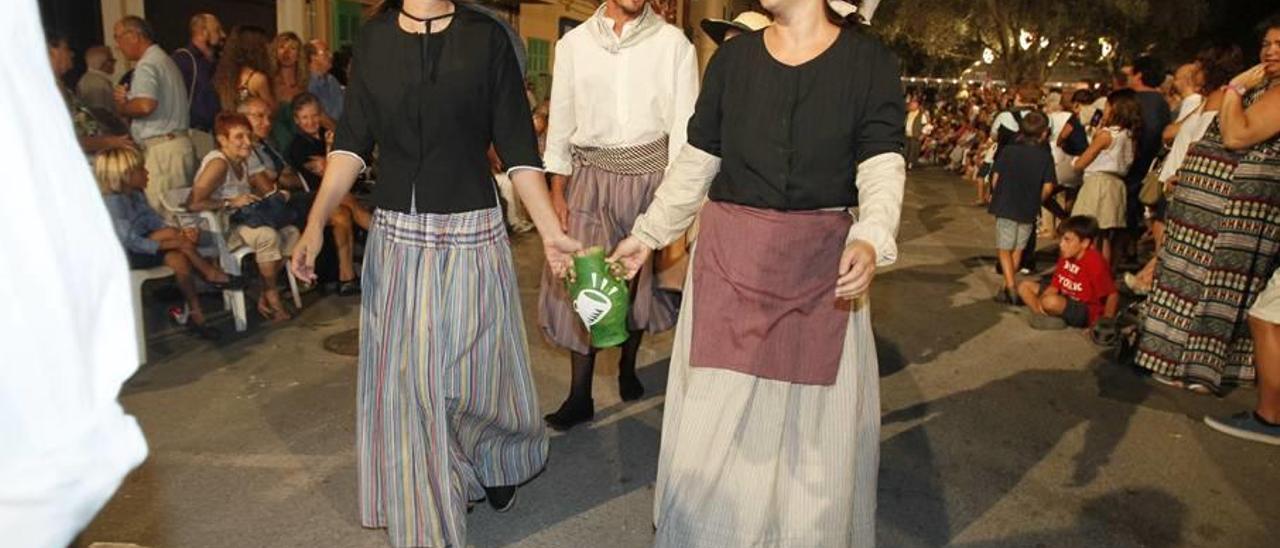 Dos payesas llevan una de las jarras que reparten los organizadores durante la procesión.