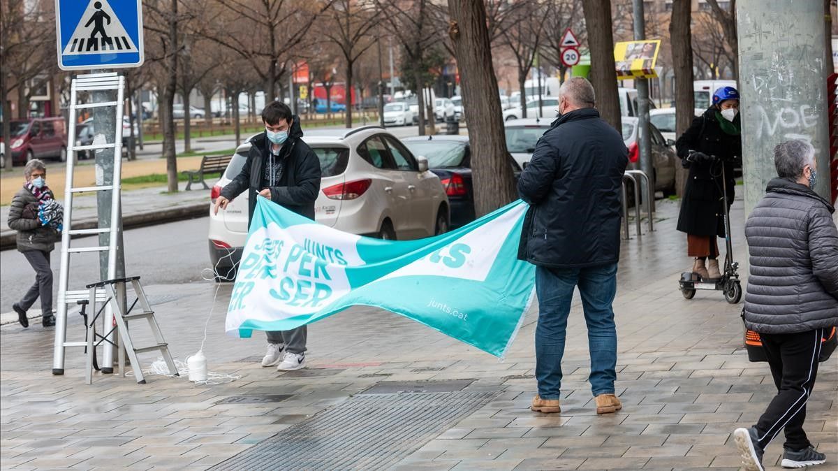 Dos militantes de Junts per Catalunya cuelgan un cartel electoral en las calles de Lleida, a menos de una semana de la cita electoral.