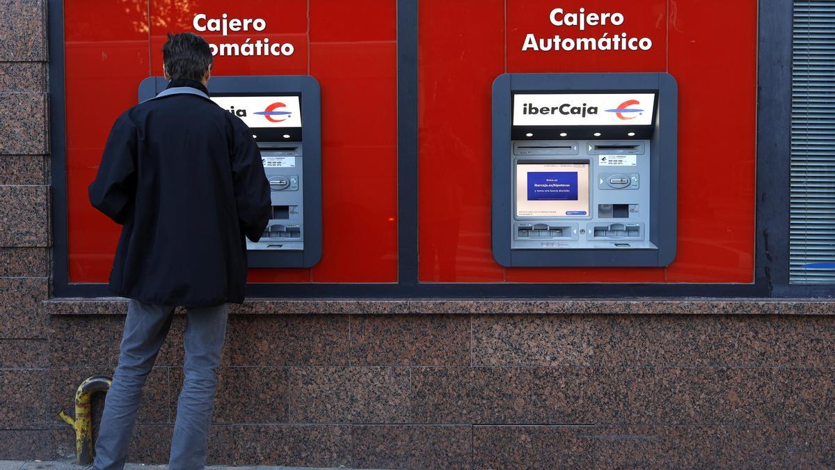 Dos personas sacando dinero en cajeros automáticos de Ibercaja