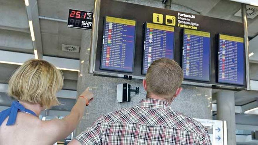 Turistas ante las pantallas de información del aeropuerto de Palma.