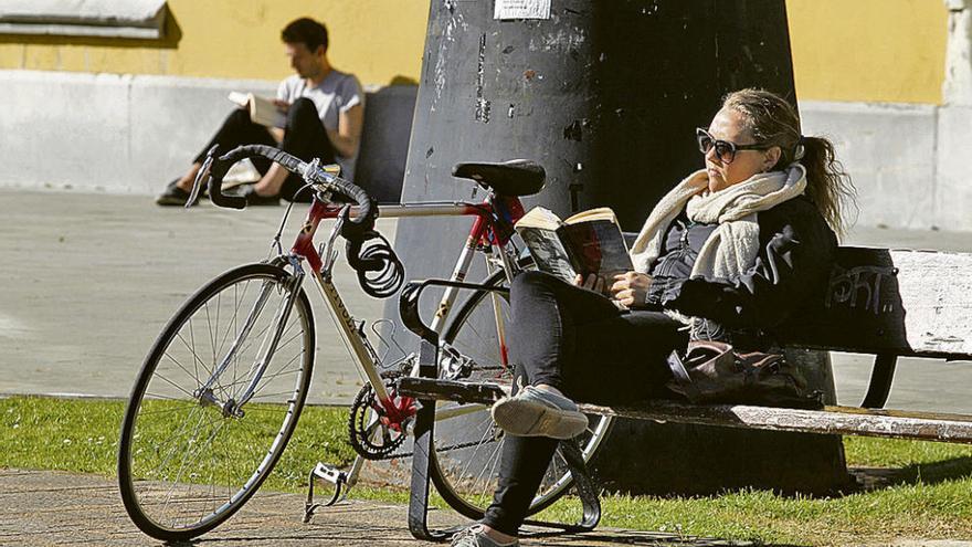 Dos personas leen libros en los jardines del campus del Milán, en Oviedo.