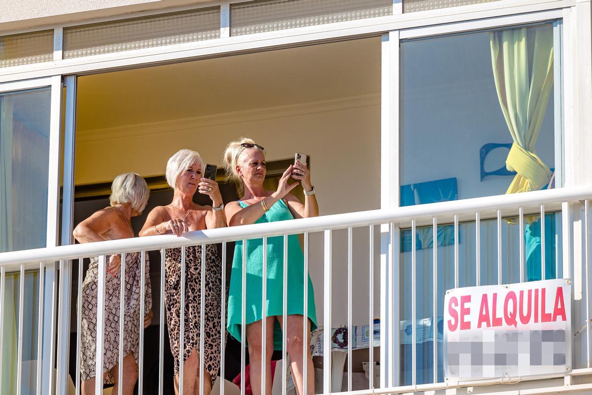Varias turistas asomadas al balcón de un apartamento vacacional en Benidorm.