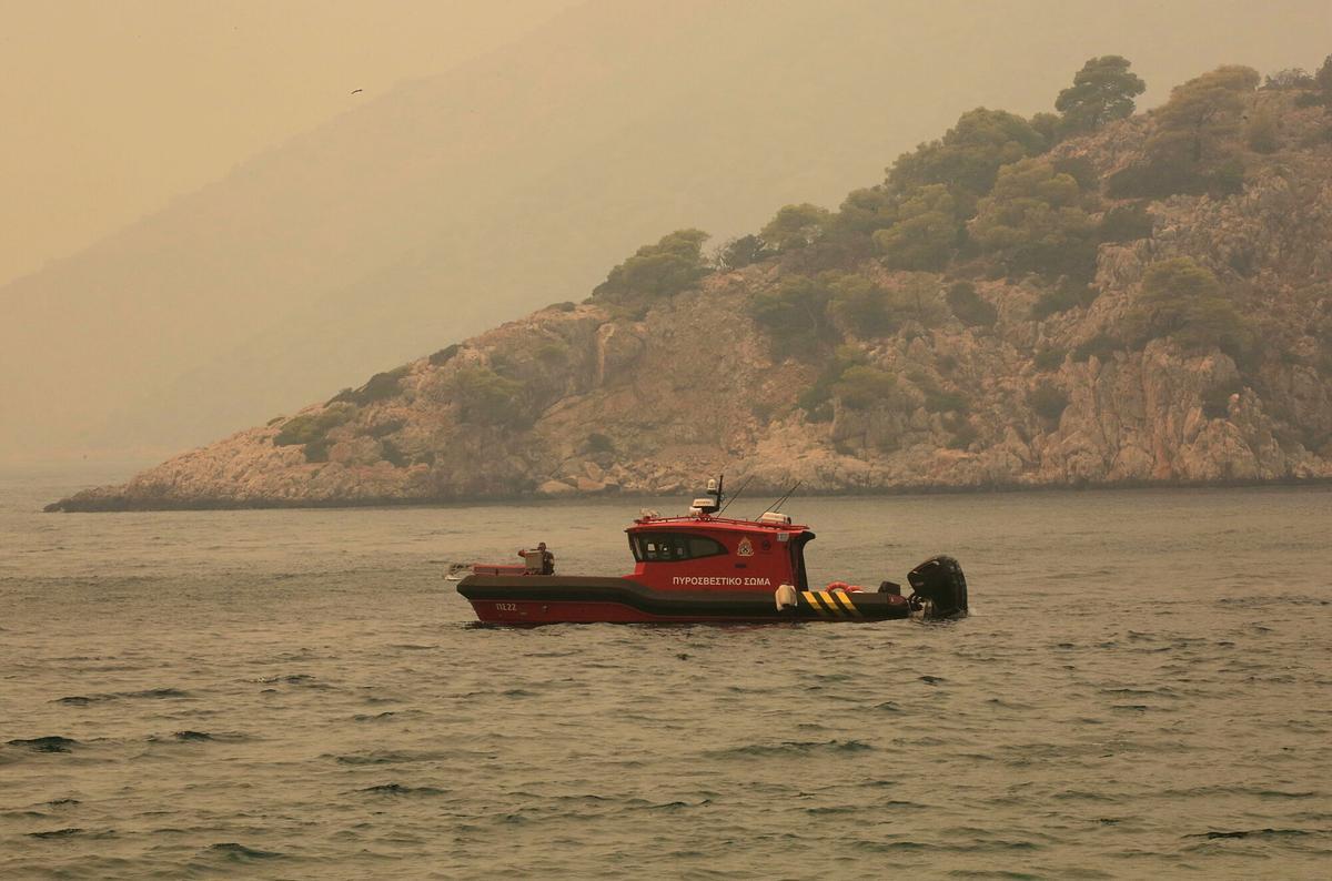 Una lancha de bomberos es alertada para transportar a los residentes en caso de evacuación en la zona, en Psatha Kontithia, durante un incendio forestal en Porto Germeno, Grecia, el 1 de agosto de 2026.