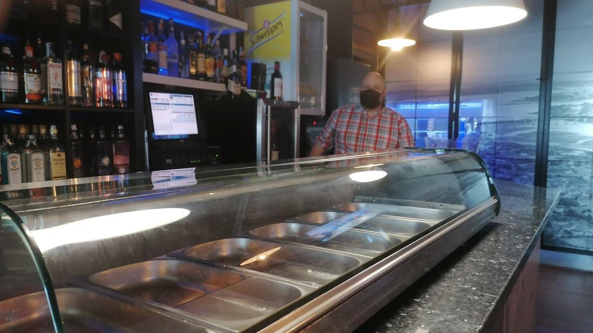 El propietario del Qubik Bar, al fondo, y en primer término las bandejas de comida vacías.