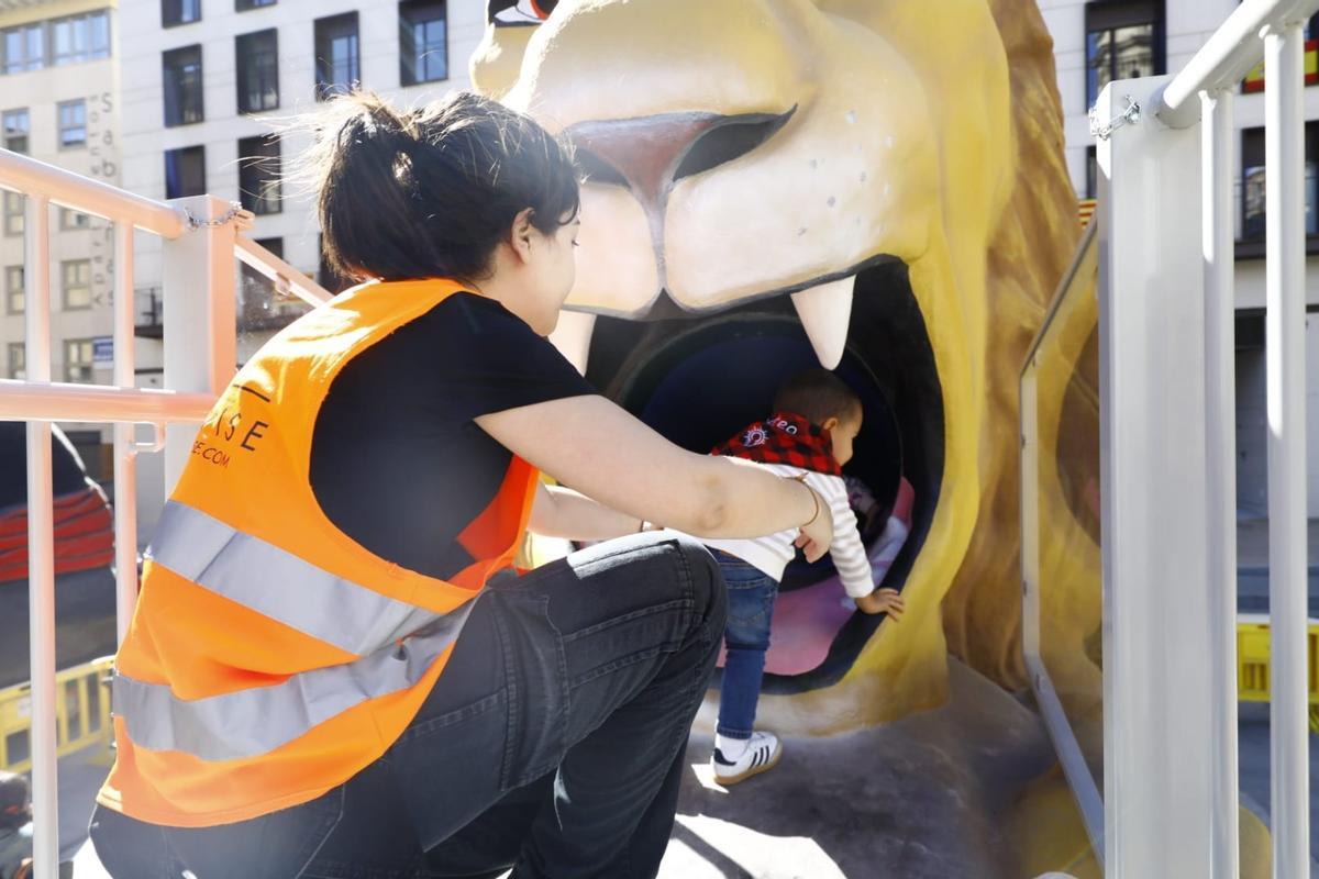 Una voluntaria ayuda a un niño a subirse por el León Garganchón.