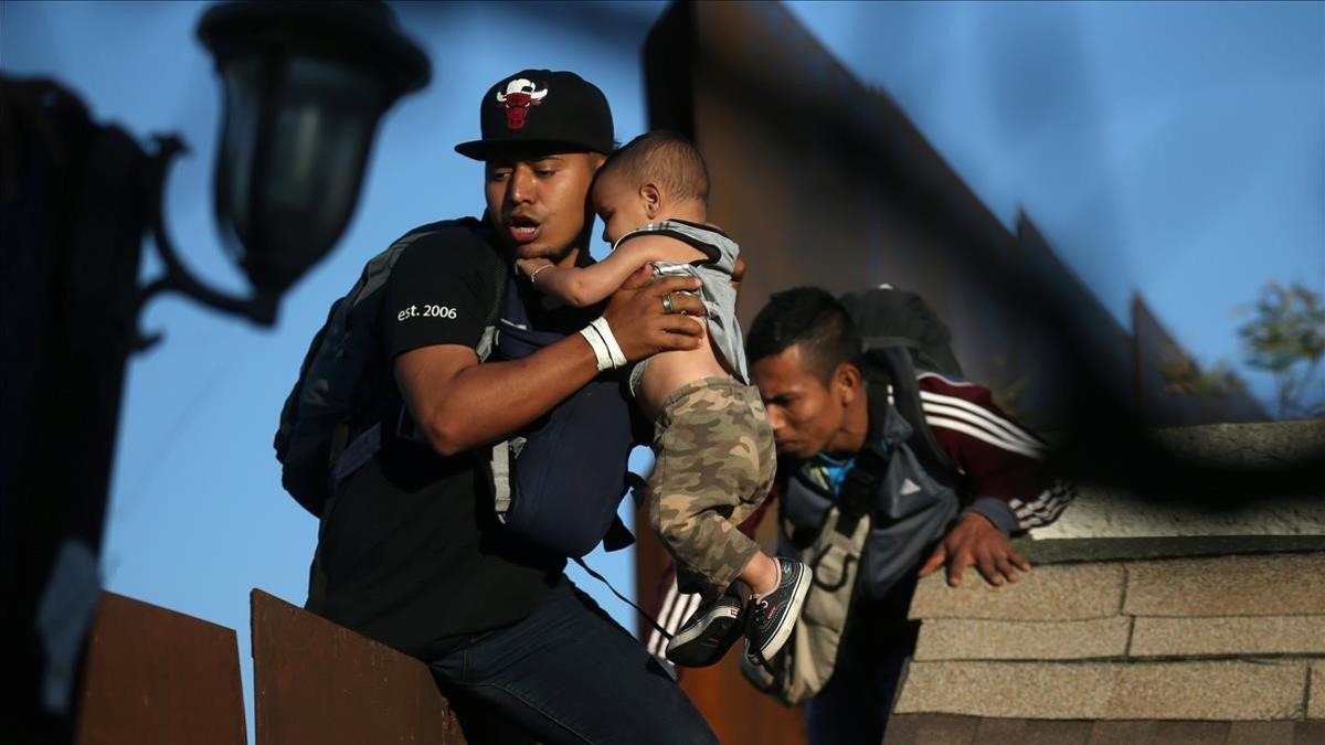Los migrantes de la caravana intentan saltar el muro desde Tijuana a EEUU