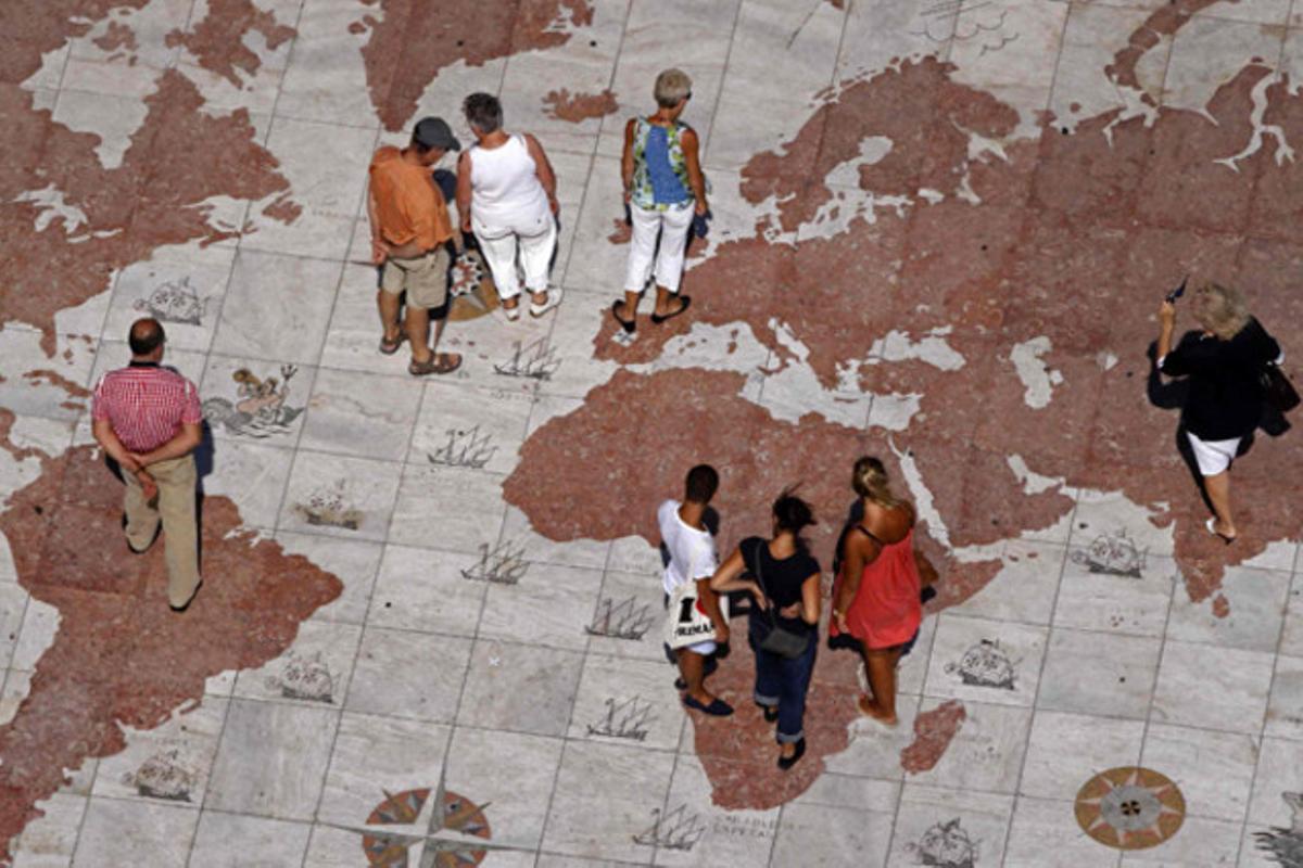 Turistes passegen sobre un mapamundi de marbre a Lisboa (Portugal).