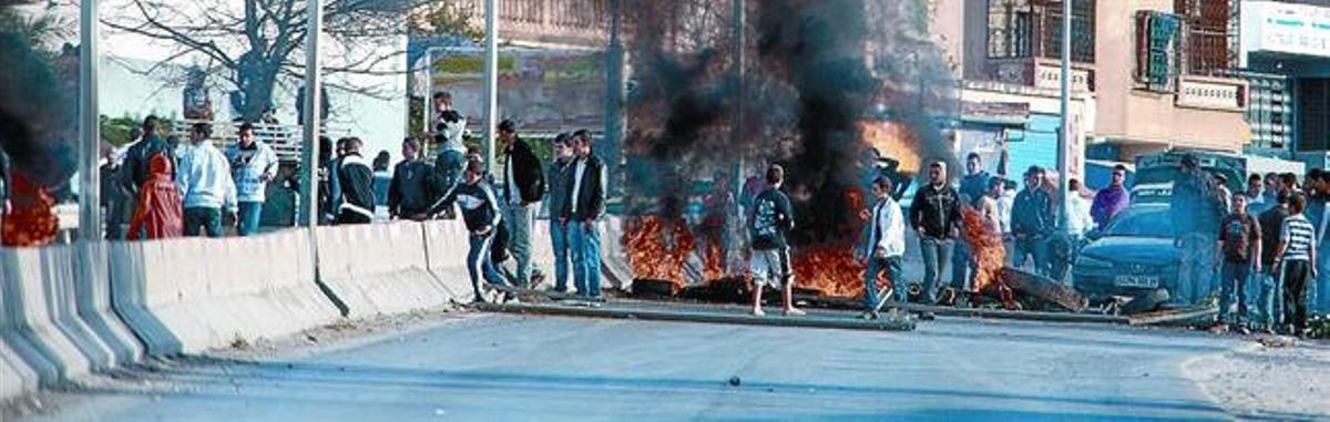Joves manifestants aixequen una barricada amb pneumàtics cremats a la ciutat de Constantine, a l’est d’Algèria.