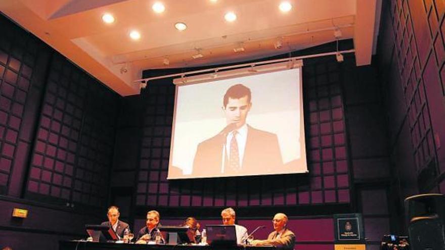 En la imagen superior, la mesa presidencial del acto, mientras se proyectaba uno de los discursos del Príncipe Felipe. A la derecha, público asistente al encuentro de ayer en Valdediós. /m. n. moro