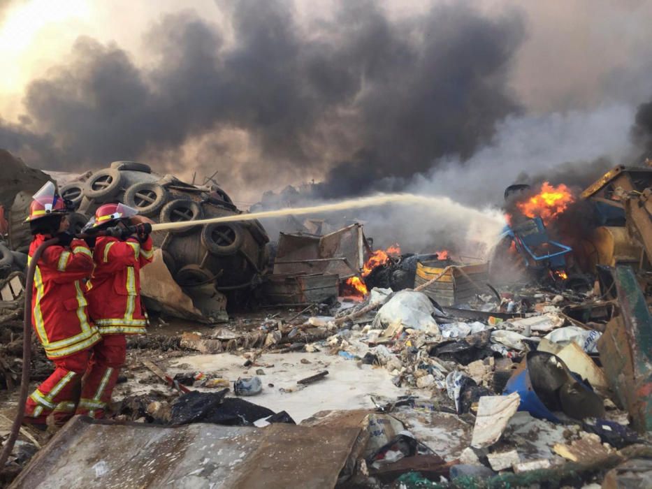 Firefighters spray water at a fire after an ...