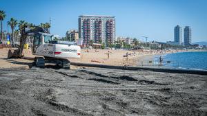 Una grúa y una tubería para arrojar arena desde un barco draga en la playa de Sant Sebastià, en Barcelona.