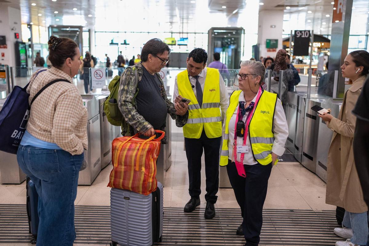 Pasajeros consultan a los informadores de Sants Estació en Barcelona ante el caos de Rodalies.