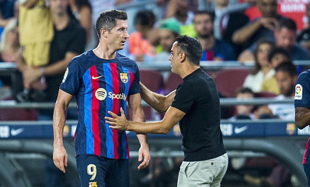 Xavi se dirige a Lewandowski en la banda.