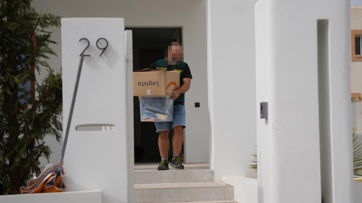 Un agente de la UCO de la Guardia Civil extrae una caja con material decomisado de una vivienda de Santa Gertrudis.