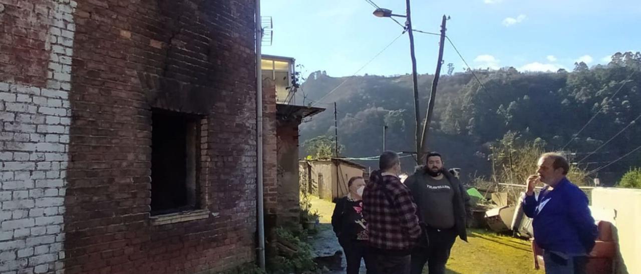 Familiares y vecinos, ayer, en la parte trasera de la casa, la más castigada por el fuego.