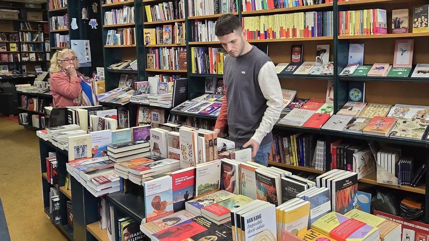 Dos personas observan los títulos en uno de los estantes de una librería.