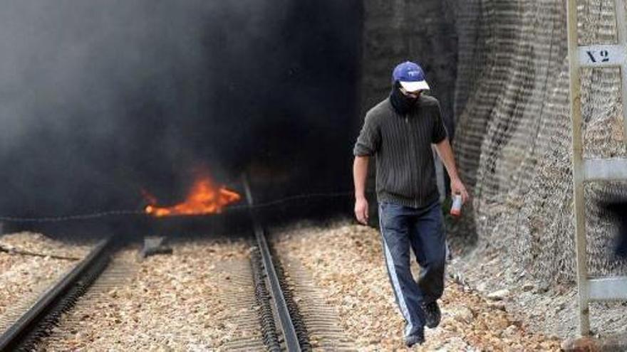 Un piquete abandona un túnel de la línea Gijón-León en Ciñera de Gordón, tras prender fuego a una barricada.
