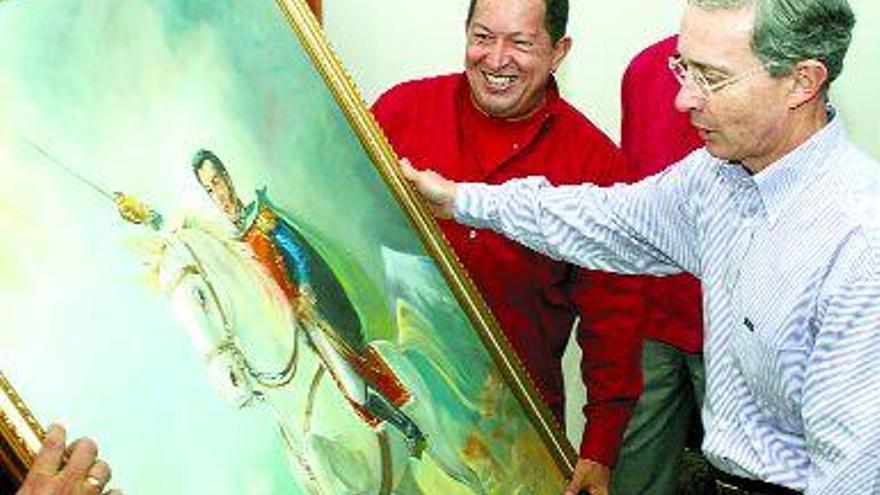 Álvaro Uribe sostiene un cuadro de Simón Bolivar, regalo de Hugo Chávez (en segundo término). / efe