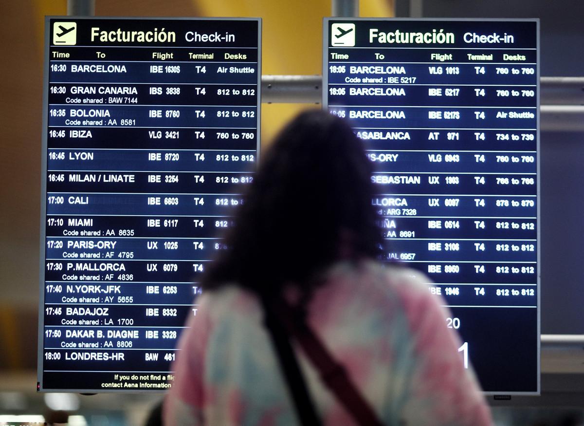Una pasajera observa un cartel de vuelos en el aeropuerto de Madrid.