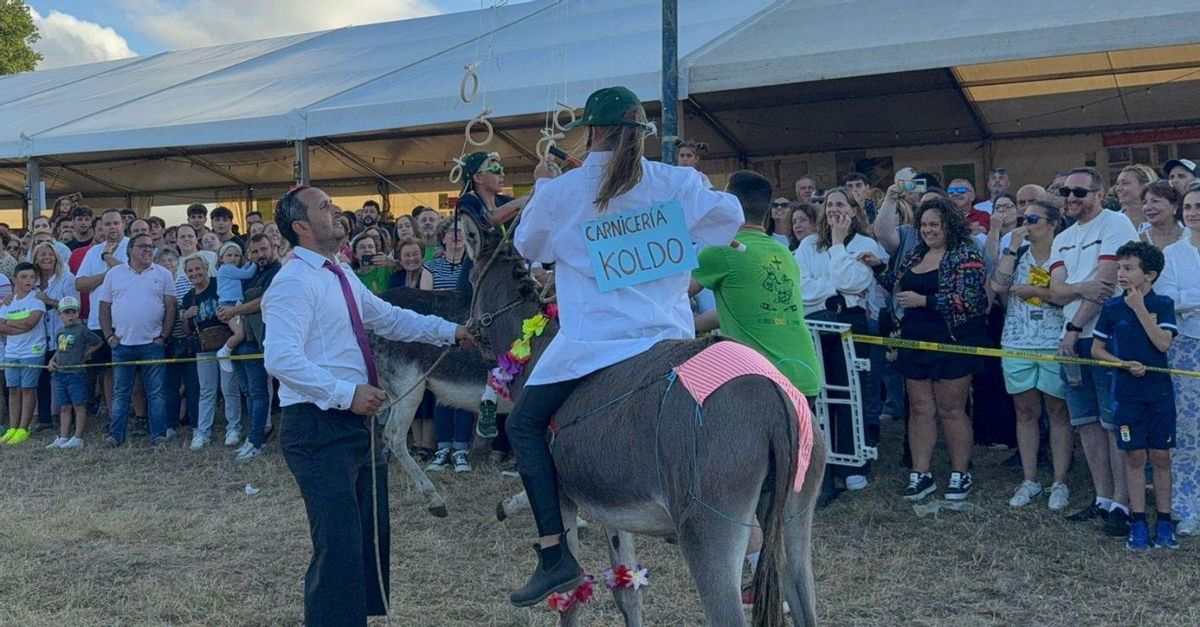 Marcos Argüelles sujeta al burro mientras Paula Rodríguez trata de conseguir su arandela.