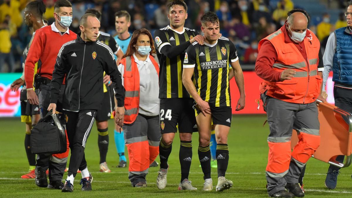 Chavarría, consolado por Lluís López, se retira lesionado en el estadio de Gran Canaria.