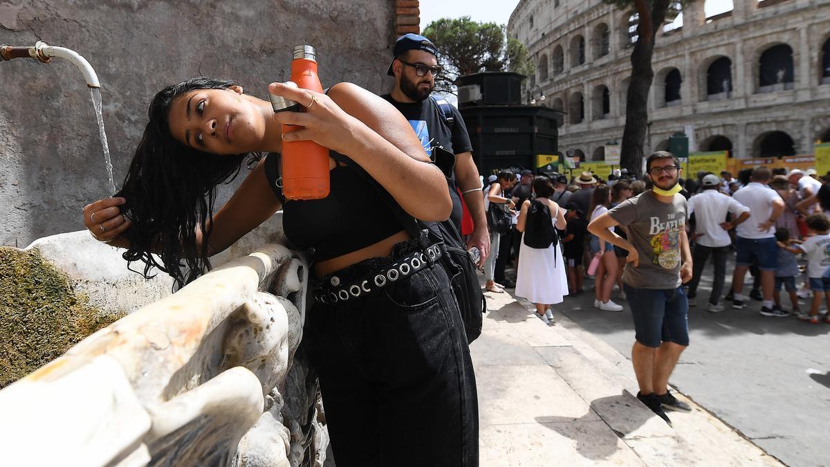 Una joven mojándose el pelo para refrescarse del calor en Italia.