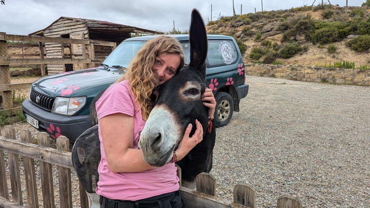 Laura García, que habla con los animales, abraza a su burra Lola, que da nombre a su residencia canina.