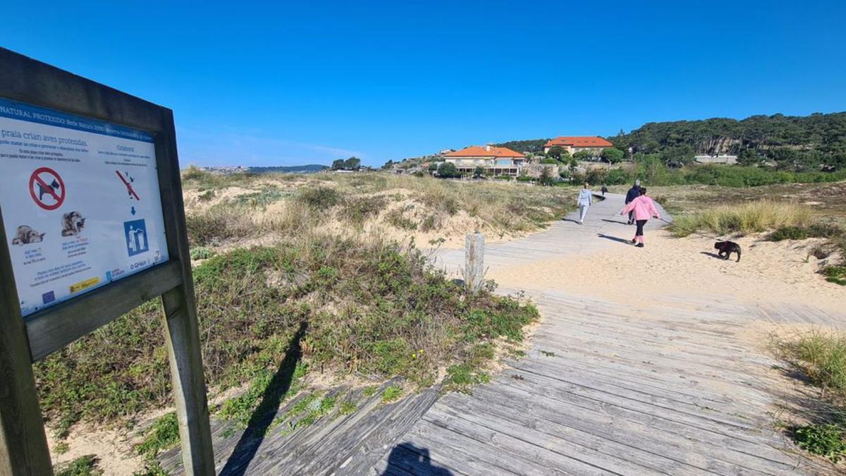 Una mujer respeta las normas y evita acceder con su perro, que lleva atado, a la playa de A Lanzada.   | // M.M.