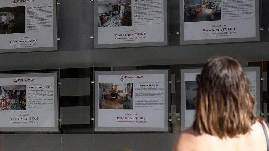 Una joven mira el escaparate de un local inmobiliario en la ciudad de Murcia.