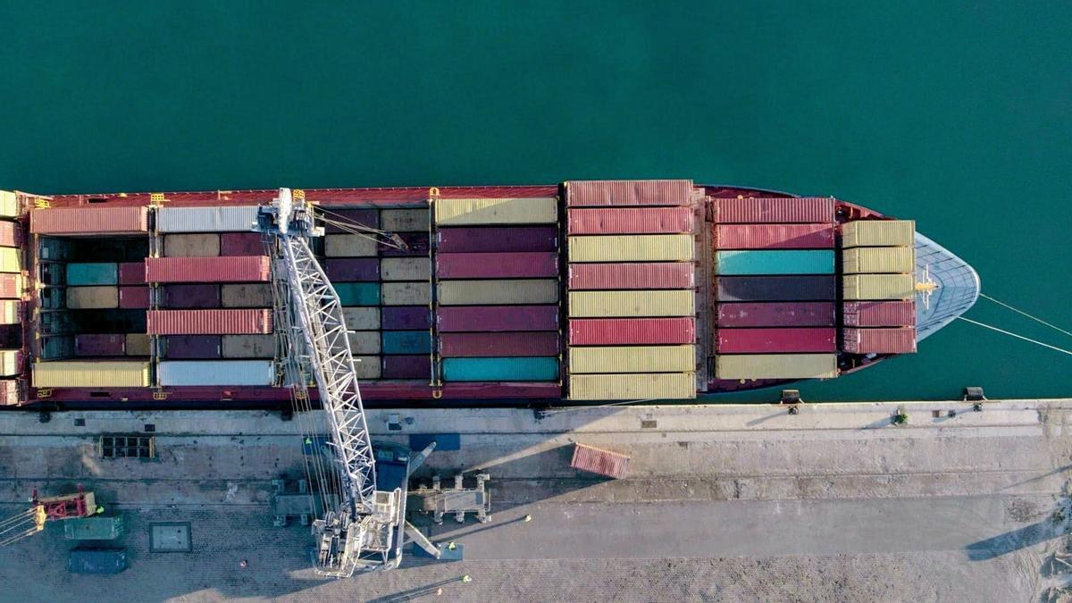 Panorámica aérea, tomada por un dron, de un buque portacontenedores durante la carga de mercancías y productos en el puerto de Almería