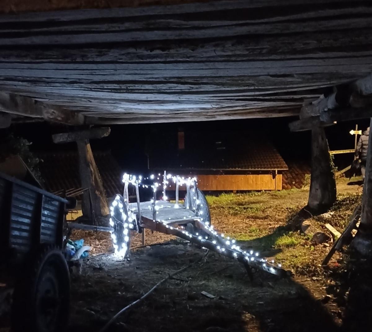 Un carro del país iluminado bajo un hórreo en Aciera.