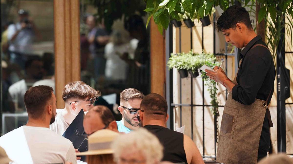Un camarero atiende a unos clientes en un establecimiento de hostelería de Málaga.