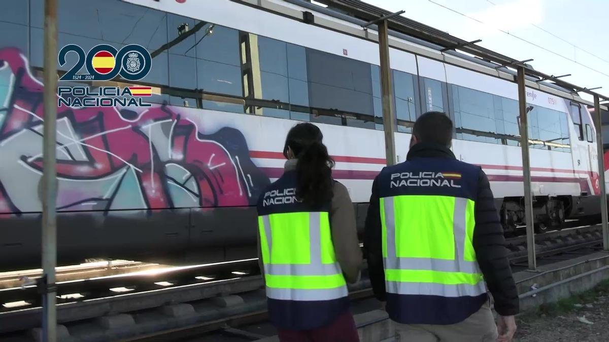 Dos agentes revisan un vagón de tren pintado con un grafiti.