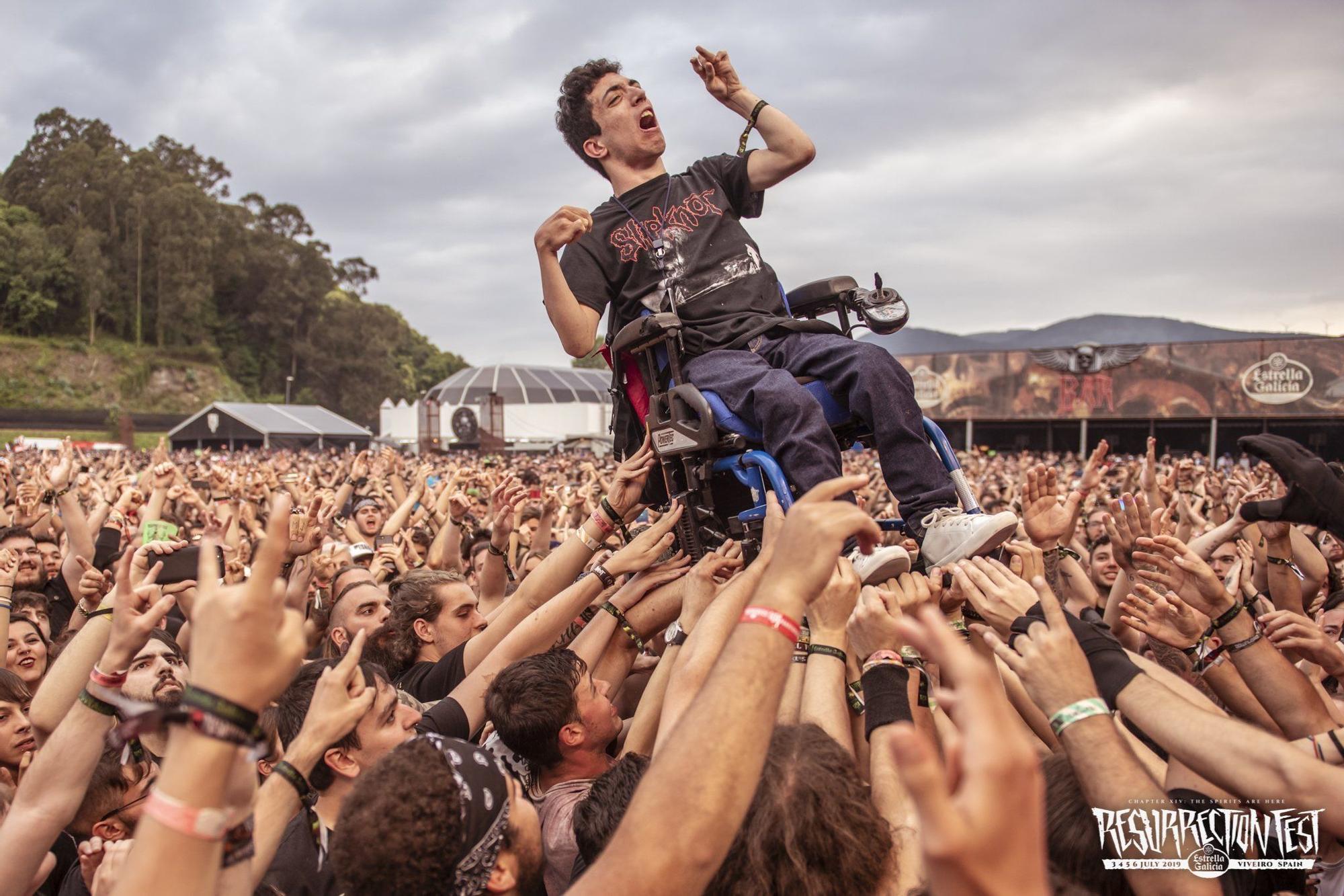 Decenas de jóvenes levantan a pulso la silla de ruedas de un chico con parálisis cerebral durante el concierto de Trivium en el festival Resurrection Fest en su última edición de 2019.