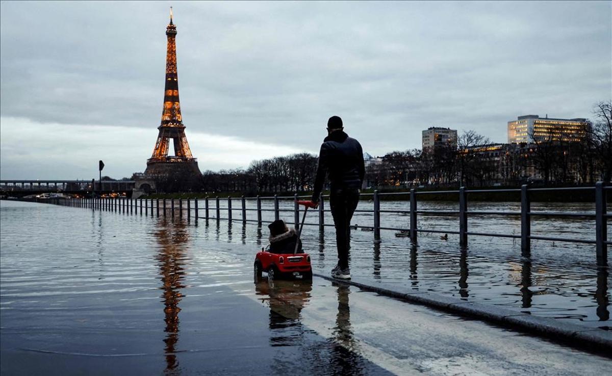 Un hombre y un niño pasean por una calle inundada cerca de la Torre Eiffel, en París, tras el desbordamiento del río Sena, en febrero del 2021.