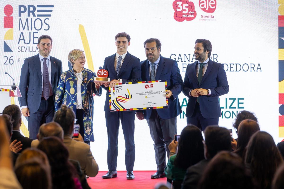 David Suárez ha sido galardonado en 2026 con el premio de la Asociación de Jóvenes Empresarios de Sevilla. En el centro de la imagen. Y junto a él Carmen Vargas, rectora de la Universidad de Sevilla; Iván Pestaña, presidente del Consejo Social de la Universidad Pablo de Olavide; Miguel Ángel Pérez, presidente de AJE Sevilla, y Félix Almagro, presidente de AJE Andalucía