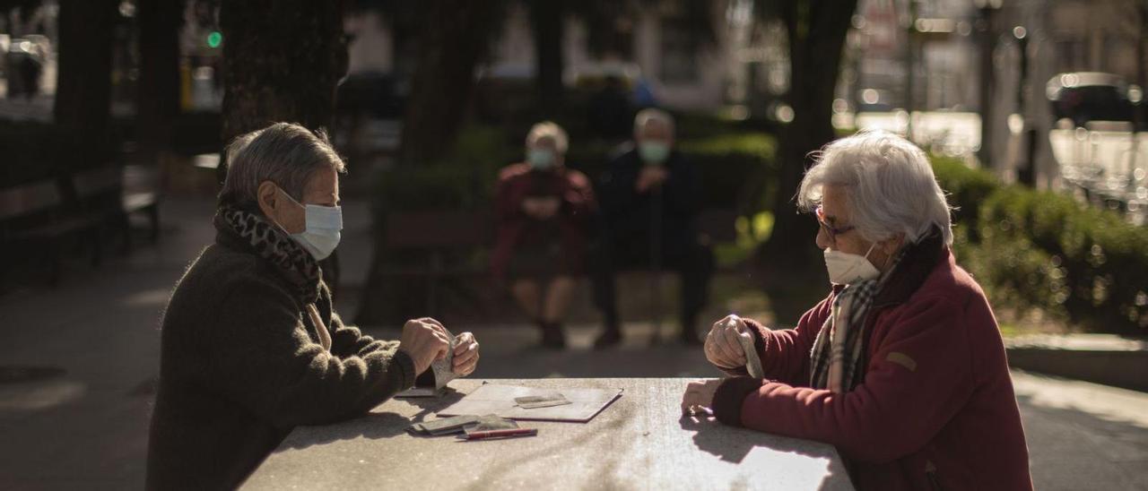 Dos mujeres juegan a las cartas ante la mirada de una pareja de mayores.