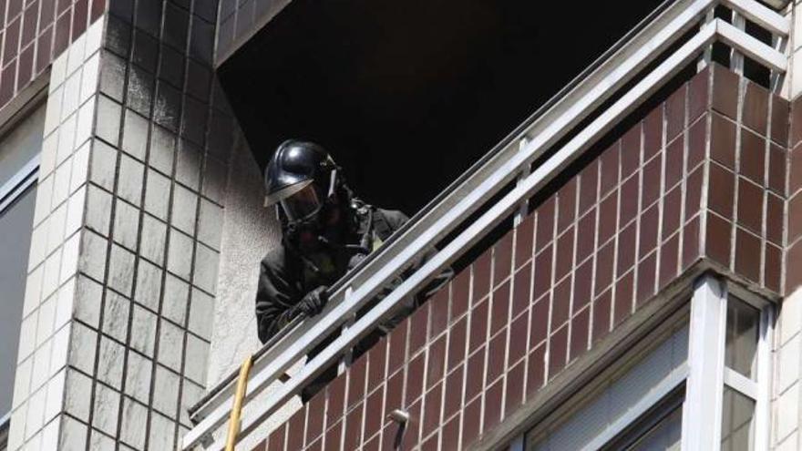 Uno de los bomberos en el balcón del piso afectado por las llamas en Travesía de Vigo .  // Ricardo Grobas