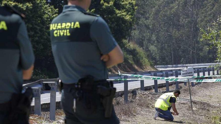 Un agente de los Tedax de la Guardia Civil recoge la granada de mortero localizada en el alto de San Antoniño. En el recuadro, detalle del proyectil. // Jose Lores