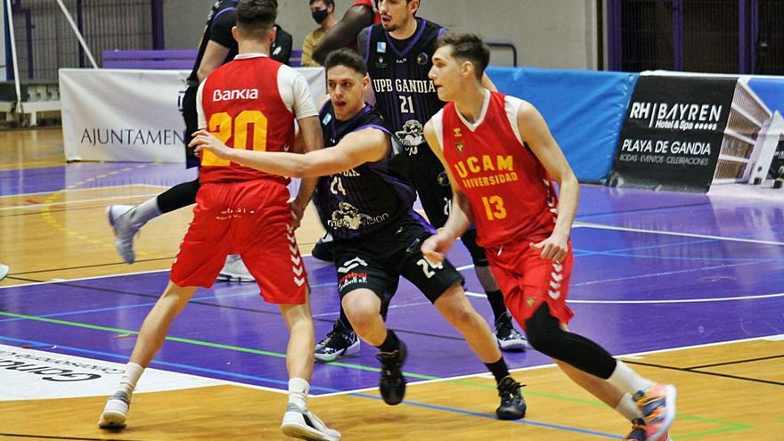 Unai Zamora, entre dos jugadores del UCAM Murcia, en un momento del partido de anoche. | LEVANTE-EMV